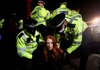 Police detain a woman as people gather at a memorial site in Clapham Common Bandstand, following the kidnap and murder of Sarah Everard, in London.