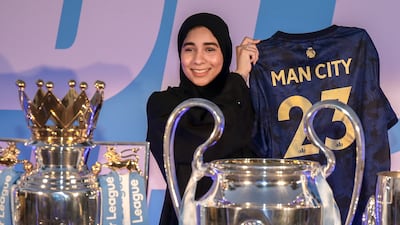 A Manchester City fan poses with the club's trophies
