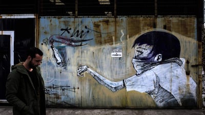 Graffiti of a man throwing a petrol bomb in the Greek capital of Athens. Greek authorities on March 17, 2017 were trying to determine how a near-defunct militant group was able to sneak at least two parcel bombs through airport security, one of which exploded at the IMF offices in Paris earlier this week. Angelos Tzortzinis / Agence France-Presse