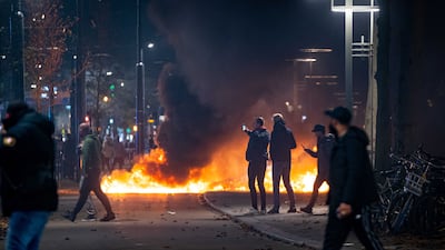 People stand near burning objects after a protest against the '2G policy' turned into riots. EPA