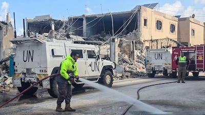 Unifil personnel pass firefighters clearing a road after an Israeli strike on the southern Lebanese town of Naqoura. AFP