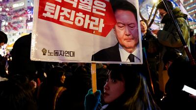 A protester holds a placard to condemn South Korean President Yoon Suk Yeol's surprise declaration of martial law. Reuters