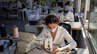 Employees feed garments through the sewing machines.