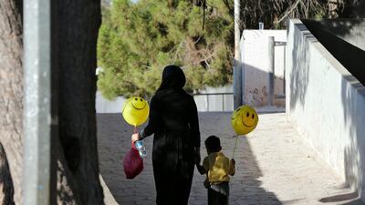 A woman and a child carry balloons after Eid Al Fitr prayers in Amman. Reuters