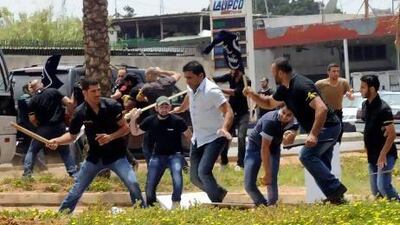 Men in black suspected to be Hizbollah supporters clash with protesters in front of the Iranian Embassy in Beirut on Sunday. AP Photo