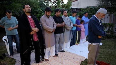 Mr Ali, above far left, in evening prayer led by Mr Ahmed, on the last day of Ramadan. Left, the father of two celebrates Eid with his family and friends at home in Palo Alto. Photos Sammy Dallal for The National