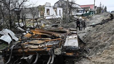 Residents walk amid debris of a charred Russian tank next to destroyed houses in the village of Zalissya. AFP