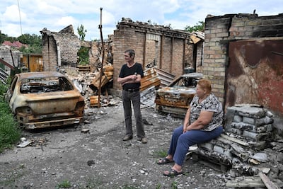 Residents wait for humanitarian aid next to a destroyed house in the town of Bucha. AFP