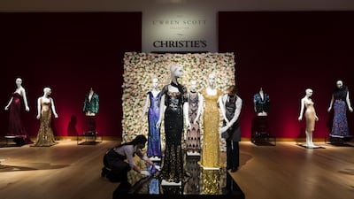 A member of staff handles a black and gold sequined 'Oscar' dress (L) worm by Nicole Kidman and a gold sequined gown (R) worn by Penelope Cruz at the L'Wren Scott Collection photocall at Christie's Auction House in London. EPA/Vickie Flores