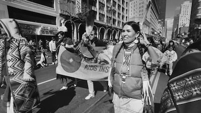 Littlefeather adorned with tribal, beaded pigtail decorations and a feather in her hair as she wears a down jacket over a squaw dress while marching in a street parade in San Francisco. Getty Images