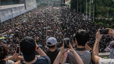 People take photographs as protesters match on the road below beneath during a demonstration against the now-suspended extradition bill in Hong Kong. Getty Images