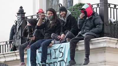 People sitting on the balcony of a west London mansion belonging to Russian oligarch Oleg Deripaska, with a banner reading, 'This property has been liberated'. EPA