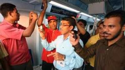 Passengers take photos from on board the first train of the day on the Dubai Metro.
