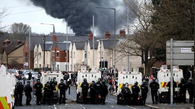 Police form a line to stop Nationalists and Loyalists attacking each other, as a hijacked bus burns in the distance in Belfast, Northern Ireland, April 7. AP