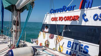 A crew member of the Carrefour floating shop watches as Marie Byrne's yacht comes alongside. Antonie Robertson / The National