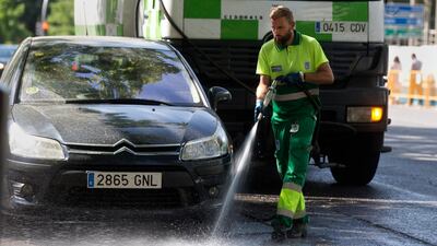 A municipal worker hoses down a street in Madrid, Spain. AP