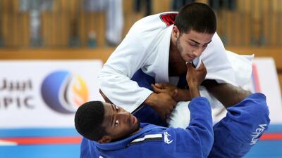 Abdullah Aljneibi, bottom, of the Al Jazira Jiu-Jitsu club, checks the remaining time while keeping a tight hold on his opponent from UAE JJF Training Center, during their match in the first leg of the inaugural President's Cup, an open competition for clubs. The event was held at the Ipic Arena at Zayed Sports City in Abu Dhabi on Saturday, August 27, 2016. Aljneibi won the match. Delores Johnson / The National