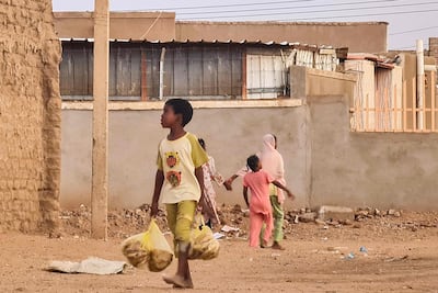 A child carries bags filled with bread as he walks in a street in Khartoum. AFP