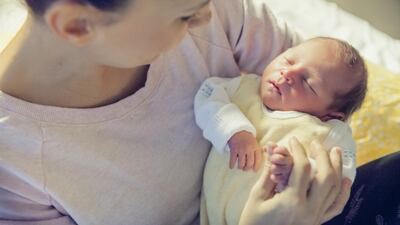 Mother holding her newborn baby in hospital bed. Getty Images