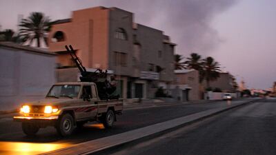An armored vehicle speeds on the outskirts of Tripoli, as huge smoke rises over the downtown, late Monday, Aug. 22, 2011. Libyan rebels claimed to be in control of most of the Libyan capital on Monday after their lightning advance on Tripoli heralded the ???