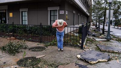 A man saves his hat in the strong wind during Hurricane Sally landfall in Mobile, Alabama. AFP