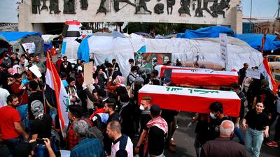Protesters carry symbolic Iraqi flag-draped coffins of people who have been killed in anti-government protests, during a rally in Baghdad, Iraq. AP Photo