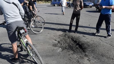 People look at an impact of shell on September 7, 2014 after an overnight bombing attack, at an Ukrainian army checkpoint in the outskirts of the key southeastern port city of Mariupol. Philippe Desmazes/AFP Photo