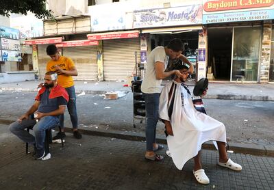 Barbers shave their customers outside their shop owing to a power cut in Beirut, Lebanon on August 20, 2021. The country has been facing a severe economic crisis since 2019. Reuters