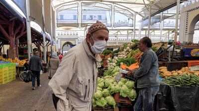An elderly man wearing a face mask due to the COVID-19 coronavirus pandemic walks with a crutch at the central market in the Tunisian capital Tunis. AFP
