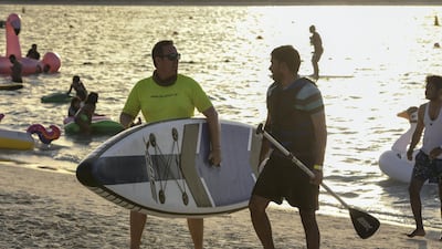 People enjoy stand up paddling at the Club Social festival on Yas Beach. Khushnum Bhandari for The National