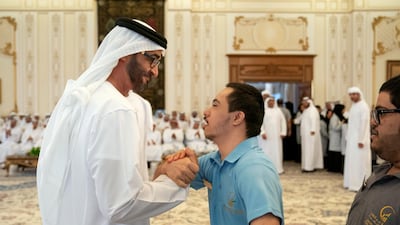 Sheikh Mohamed shakes hands with a member of Zayed Higher Organisation for People of Determination.