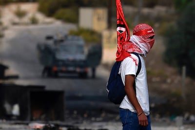 A Palestinian youth carries a PLFP flag during clashes with Israeli troops at the northern entrance of the West Bank city of Ramallah. AFP