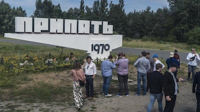 Tourists stop for pictures at a sign marking the entrance to the abandoned city of Pripyat. Getty Images
