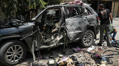 First responders inspect the wreckage of a car reportedly targeted by an Israeli strike in Nabatieh. AFP