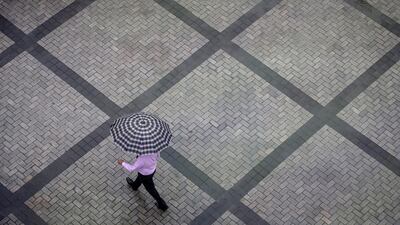 An office worker holding an umbrella walks out of a commercial building as it rains in Mumbai's central financial district. Danish Siddiqui / Reuters