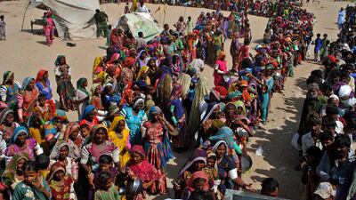 People from flood-affected areas wait for food distributed by a charity in southern Sindh province, Pakistan. The country has been devastated by deadly floods amid rising global temperatures. AP