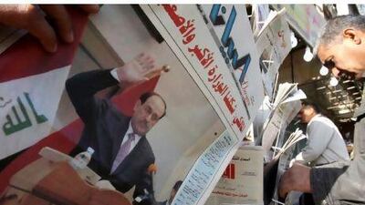 Iraqis pick up newspapers yesterday featuring a front-page story on the inauguration of the new government. Ali al-Saadi / AFP