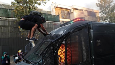 A protester jumps on a burning police vehicle during a protest against Chile's government in Santiago. Reuters