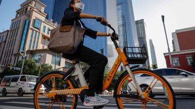 A woman rides a bicycle in the central business district of Beijing. China's surveyed unemployment rate eased to 5.5 per cent from May's 5.9 per cent. EPA