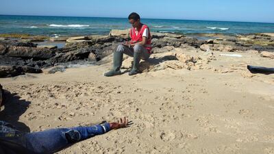 A body of a drowned migrant (L) lays in the sand, off the shore of Gasr Garabulli, in the eastern city of Tripoli, Libya. EPA