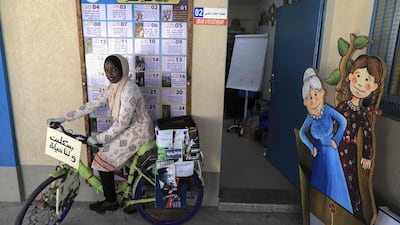 A Palestinian volunteer rides a bicycle used to distribute crafts and reading material to children in confinement due to the coronavirus at the central Deir al-Balah refugee camp in the Gaza Strip. AFP