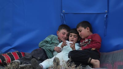 Internally displaced Syrian boys play on a mobile phone outside a tent in Azaz, Syria. REUTERS