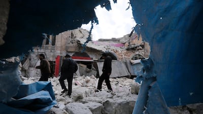 People walk past destruction by the government airstrikes in the town of Ariha. AP Photo