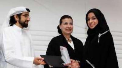 Sheikh Sultan Sooud al Qassemi presents Al Anoud al Shaibani of UAE University with a graduation certificate while Hoda Al Khamiss Kanoo looks on.