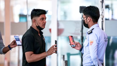 Al Wahda Mall security staff check the Al Hosn app of visitors at the entrance. All photos: Victor Besa / The National