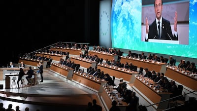 French President Emmanuel Macron is shown on a big screen as he delivers a speech at the One Planet Summit. Eric FEFERBERG/AFP