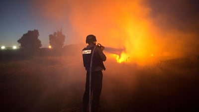 An Israeli firefighter extinguishes fire after rockets fired by Palestinian militants from the Gaza strip hit a field near the southern Israeli city of Sderot. Israel and Palestinian militants resumed fire across the Gaza border, sparking panic across the war-torn enclave and halting truce talks. Menahem Kahana / AFP