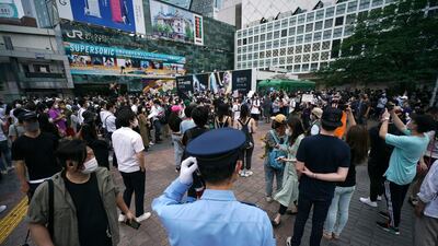 A police officer stands near people gathering to protest during a solidarity rally for the death of George Floyd on Saturday. AP