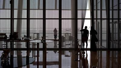 Visitors, seen through the blinds of the lobby windows, take in the sights of the Dubai Creek at the Crowne Plaze hotel. Antonie Robertson / The National
