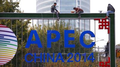 A man takes pictures of workers installing lighting on an APEC sign post at the financial district in Beijing, on October 28, 2014. Countries at an Asia-Pacific summit in Beijing pledged to pursue "flexible" fiscal policies to support the world economy and job creation, their finance ministers said in a joint statement on Wednesday. Petar Kujundzic / Reuters